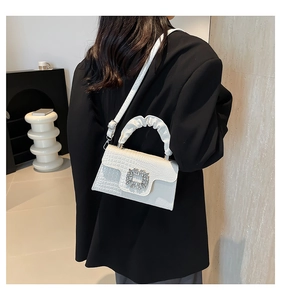 White croc-effect handbag featuring a pleated handle and a sparkling rhinestone buckle