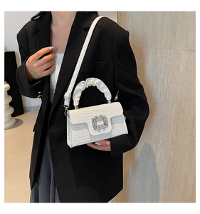 Close-up of white crocodile pattern bag with a crystal buckle and ruffled handle