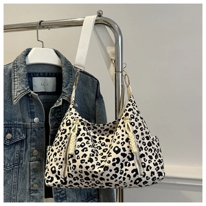 Detail of leopard print tote bag with wide strap and side pockets on denim background