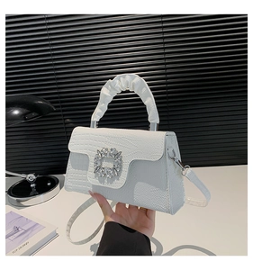 Close-up of white crocodile pattern handbag featuring a sparkling rhinestone buckle detail