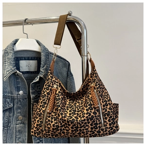 Detail of leopard print tote bag featuring wide fabric straps and decorative zippers