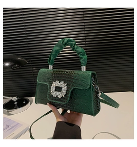 Detailed view of dark green croc-effect handbag with crystal buckle and ruched handle