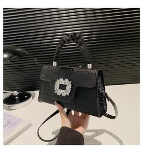Detail of black crocodile texture handbag with rhinestone buckle and pleated handle