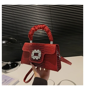 Detail of burgundy crocodile texture bag with sparkling crystal buckle and pleated handle