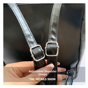 Detail of adjustable leather strap with silver metal buckle on a black tote bag