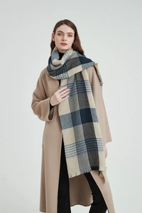 Detail shot of the thick blue and beige plaid scarf with fringed edges and soft texture
