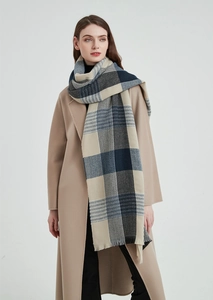 Close-up of thick blue plaid scarf with fringes styled on a camel wool winter coat