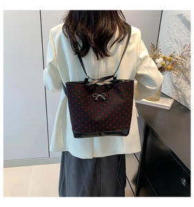 Detail of black heart pattern tote bag with silver bow buckle on white blazer outfit