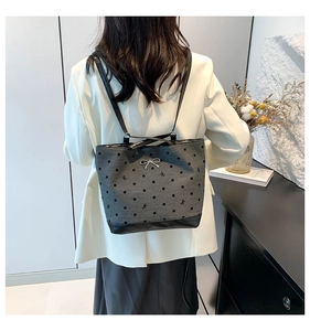 Detail view of dark grey polka dot canvas tote bag with black leather straps and metal bow