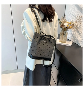 Detail of grey bucket bag with black polka dots and bows worn by a model in casual style