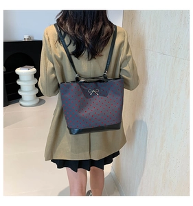 Detail of grey polka dot backpack with silver bow accent on model in khaki blazer