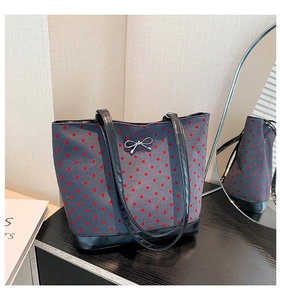 Close-up of canvas tote bag with red heart patterns and silver bow metal hardware