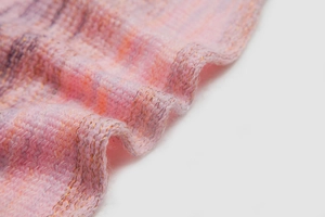 Macro shot of pink and purple gradient knit fabric with subtle gold metallic threads