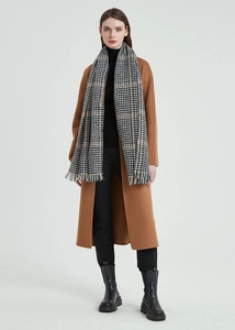 Classic black and white houndstooth scarf with fringe styled on a long camel wool coat
