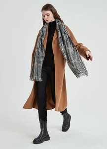 Full-body shot of a chic winter outfit featuring a houndstooth scarf and camel coat