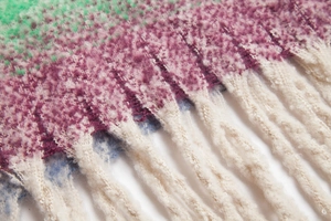 Nahaufnahme von buntem Farbverlauf-Strickschal aus Schlingengarn mit langen flauschigen Fransen