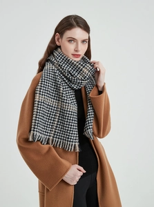 Detail of classic black and white houndstooth scarf with tassels on brown wool coat