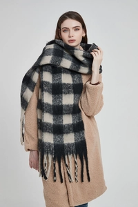 Détail d'une écharpe à carreaux noir et beige avec franges sur un manteau teddy