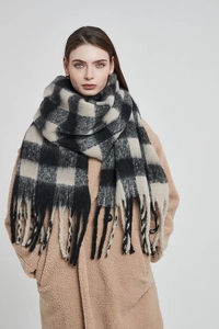 Détail d'une écharpe épaisse et douce à carreaux noir et beige avec de longues franges