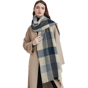 Woman in beige coat wearing soft thick blue plaid scarf with fringes for winter warmth