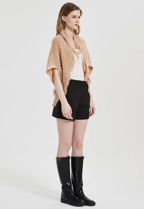 Detail of knit cape shawl featuring striped patterns and elegant fringe trim on edges