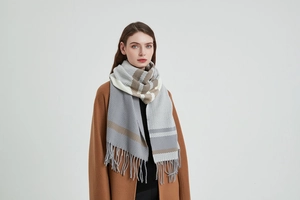 Detail of gray plaid scarf with fringe tassels worn over a camel wool coat