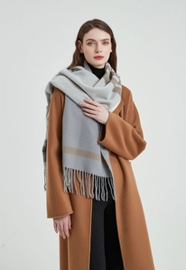 Detail of grey and white striped scarf with tassels paired with a caramel coat