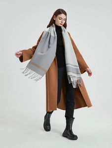 Detail of grey and khaki plaid scarf with fringe showing soft wool blend texture