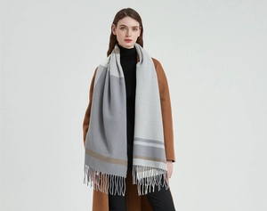 Close-up of grey and brown striped winter scarf showing soft cashmere texture and tassels
