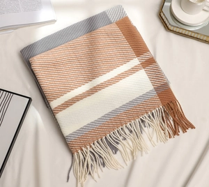 Detail of plaid scarf with fringe, showing grey and orange knit textures and patterns