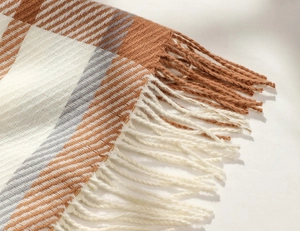 Close-up of brown and grey plaid scarf detail featuring delicate fringe and twill weave texture