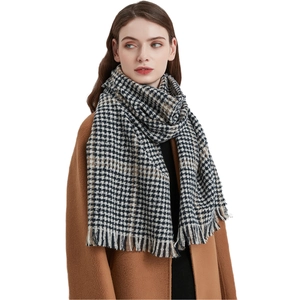 Classic houndstooth knit scarf with tassels paired with a brown wool coat on model