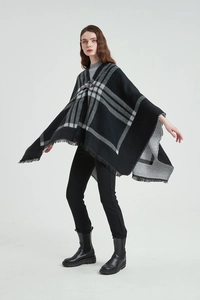 Détail d'un poncho à carreaux avec fermeture à boucle en cuir et franges élégantes