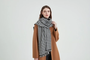 Détail de l'écharpe à motif pied-de-poule noir et blanc avec franges sur un manteau