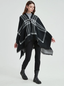 Détail du poncho à carreaux avec boucle en cuir noir et ourlet à franges douces