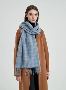 Detail eines karierten Schals mit Fransen in Blau und Camel-Mantel für den Winter