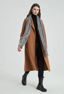 Détail de l'écharpe à motif pied-de-poule avec un manteau long de couleur camel élégant
