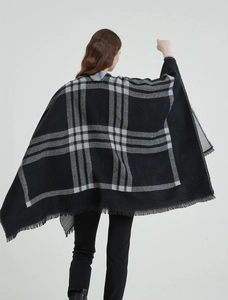 Détail d'un châle à carreaux noir et gris avec des franges élégantes et un drapé fluide