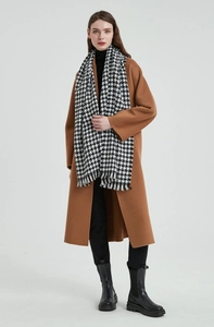 Écharpe à motif pied-de-poule noir et blanc avec franges portée sur un manteau marron