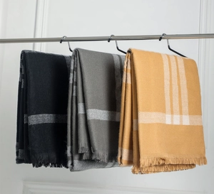 Présentation de châles à motifs géométriques et franges en jaune, gris et noir suspendus