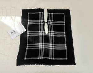 Détail d'un châle à carreaux noir et blanc avec boucle en cuir et ourlet à franges