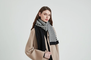 Detail of knit scarf showing houndstooth patterns and cable knit textures on a soft fabric
