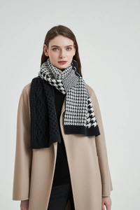 Detail of thick knitted scarf with houndstooth pattern and black cable knit texture