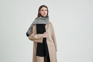 Detail of knitted scarf with black and white houndstooth pattern and black cable knit texture