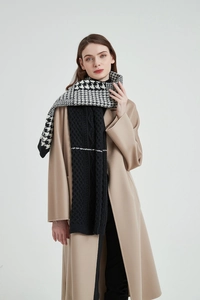 Close-up of thick knitted scarf featuring houndstooth pattern and black cable knit texture