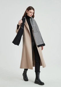 Detail shot of a black and white houndstooth scarf paired with a camel wool coat