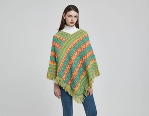 Detail of yellow bohemian knit poncho with zigzag patterns and long fringe tassels