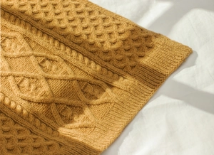 Close-up of mustard yellow thick knit scarf with intricate cable and honeycomb patterns