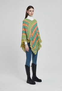 Ethnic knit poncho with wavy patterns and long fringe tassels shown on a model