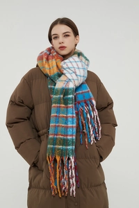 Close-up of thick rainbow plaid scarf with long tassels paired with a brown puffer jacket